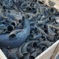 A wooden crate filled with hollow animal horns and a rubber tire, with stacked burlap sacks in the background.